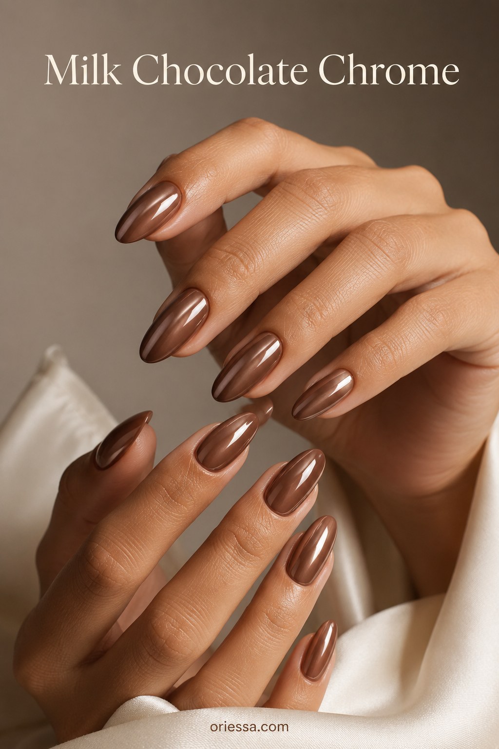 Milk chocolate chrome nails with a warm metallic almond finish glowing against deep skin tones