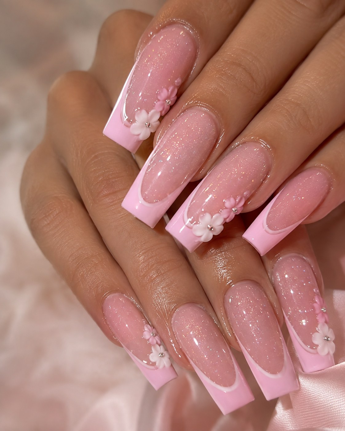 Long pink coffin nails with glitter French tips and 3D flower charms shown at full length