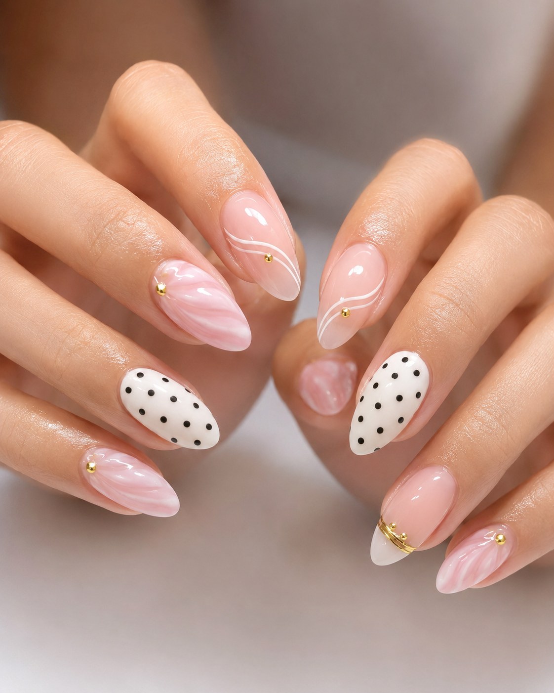Pink short nails featuring swirl marble art, polka dots, and gold studs for an elevated look